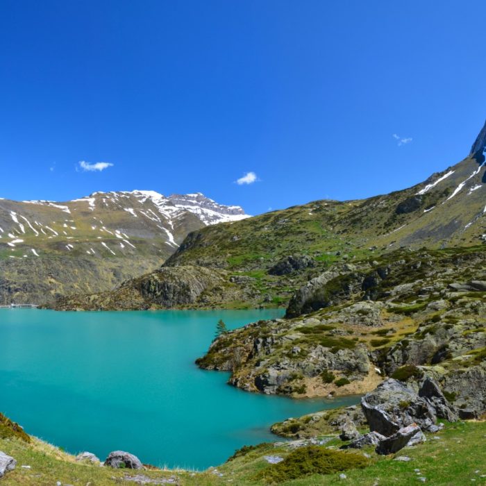 The ridge of Chourrugue is at right of the panorama with the reservoir lake Gloriettes, mountain chain of Heas Valley with the snowy Peak des Aguilous 2976 m at the background, Hautes Pyrenees, France